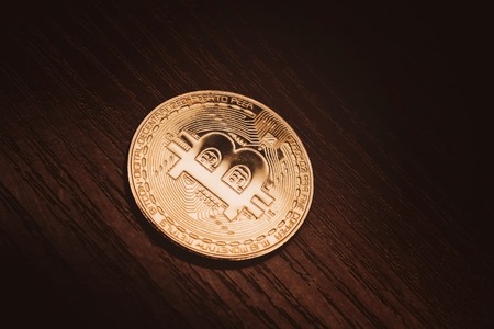 Crypto currency in gold. Gold coin bitcoin close-up against a dark wood background.の写真素材