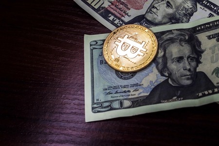 Gold coin bitcoin next to the bills of American dollarsの写真素材