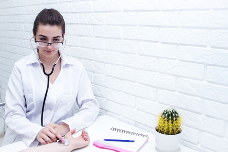 Close up of young nurse listening heartbeat with stethoscope on the old man's handの写真素材
