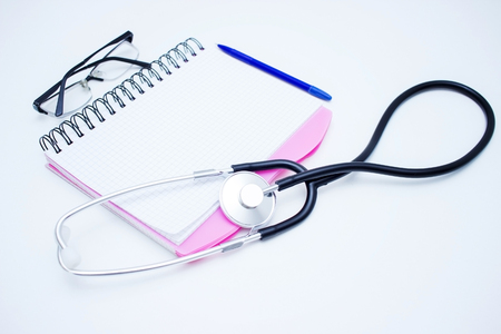 Blank notepad with stethoscope, pills, red heart and stack of book on the table. Doctor's workplace.の写真素材