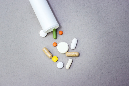Tablets on a gray background, a bottle with tablets on a gray background of different colors,...