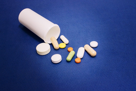Spilled tablets and medicine bottle.Tablets on a blue background