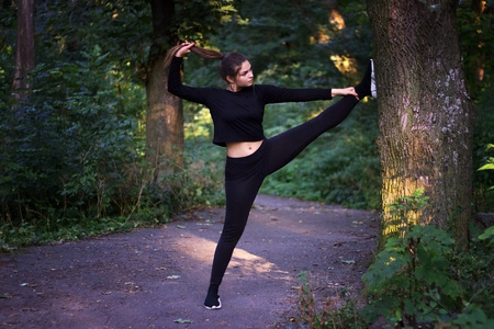 Young woman practicing yoga in park near treesの写真素材