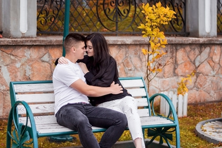 beautiful young couple sitting on a bench in the parkの写真素材
