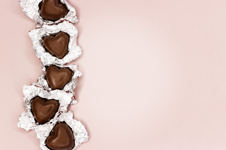 Chocolate hearts in foil on pink background