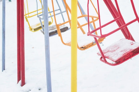 Empty swing in winter time with snow. Children's swing under a thick layer of snow