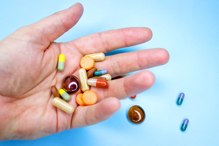 An elderly man holds a lot of colored pills in old hands. Painful old age. Health care of older...