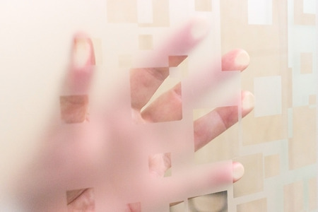 Hand behind the glass. Shadow of hand behind frosted glass.の写真素材