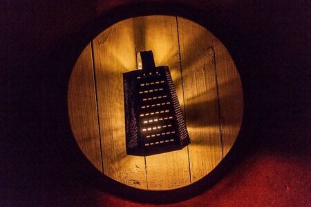 Creative lamp made of grater in the dark on a red background