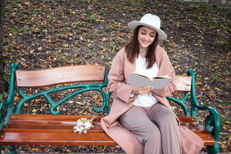 A girl reading a book in the park on a benchの写真素材