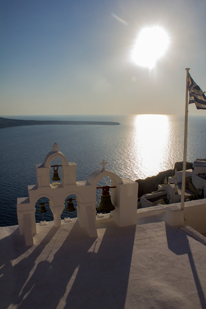 Sunset on the bell tower and the Greek flag on the island of Santorini.の写真素材