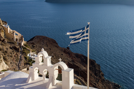 Greek flag and the orthodox church bell tower overlooking the Mediterranean Sea.の写真素材