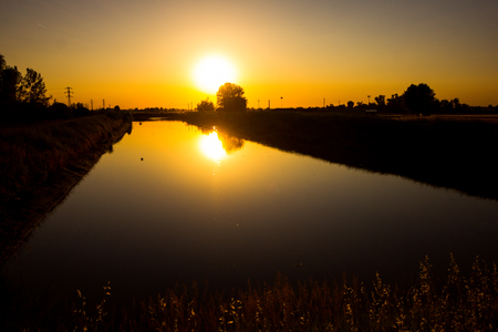 The sun is reflected in the river with a play of shadows. Castelnovo di Sotto - Italyの写真素材