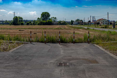 The end of the road with colored poles, delimiting the end of the road ending in a wheat field. The interruption of the creation of man towards nature.の写真素材