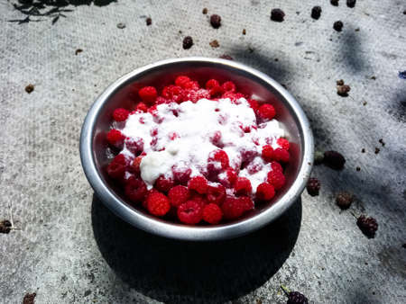 Red raspberries in a metal bowl filled with water, in a bowl without water, in a bowl sprinkled with sugar in a bowl filled with creamの写真素材