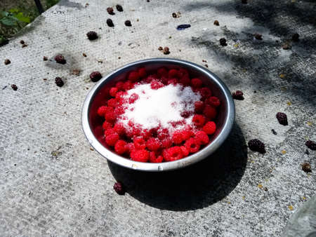 Red raspberries in a metal bowl filled with water, in a bowl without water, in a bowl sprinkled with sugar in a bowl filled with creamの写真素材