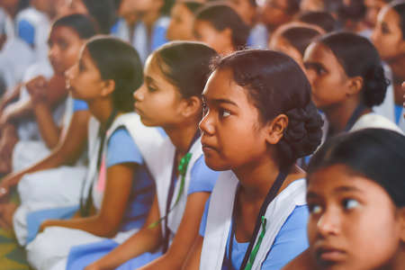 Group of young school girls  from government school sitting on floor of their classroom attending class with complete focus and interest.のeditorial素材