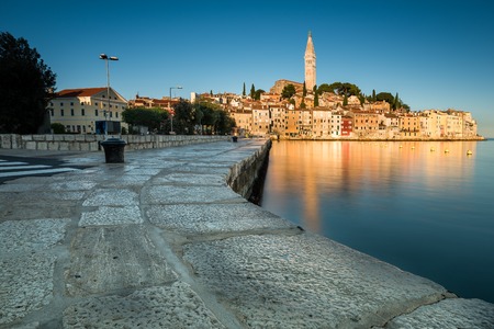 The old town of Rovinj in Croatia on a sunny morning. The sun rises and enlighten the mediterranean town Rovinj in Istria. You can see the golden reflection of the town in the sea.のeditorial素材