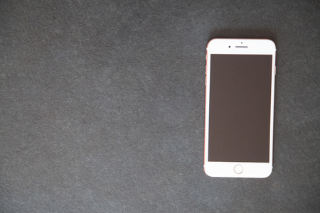white smartphone rightside on dark stone table with copyspaceの写真素材