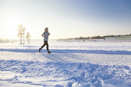 Female runs from left to right in winter landscape with backlightの写真素材