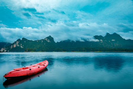 Long exposure of tropical rain forest and mountains in the background and kayak on a lake in the...