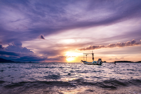 Small fishing boat on sea during a sunset with islands in the background in Koh Samui, Surat Thani, Thailandの写真素材