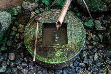 Ancient Zen stone wash basin with Japanese writings and water coming out of bamboo pipe in Ryoanji Temple, Kyoto, Japanの写真素材