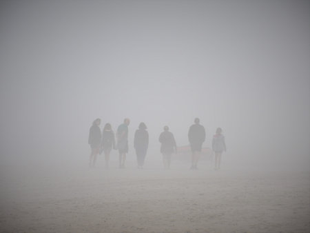 People walking on the beach in a foggy winter day in South Africaの写真素材