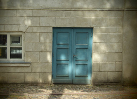 Blue door on a stone wall with shadow from the window. Vintage style.の写真素材