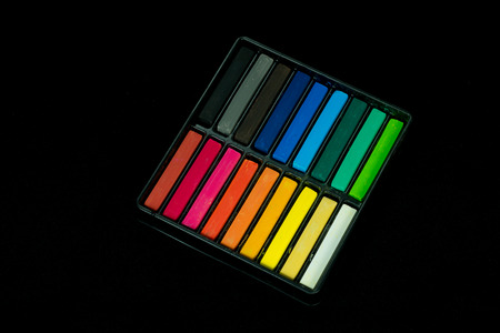 A box set of Colored chalk sticks isolated on black background.