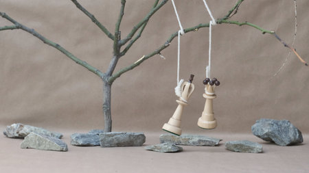 chess pieces white king and queen hanging among stones on a beige background