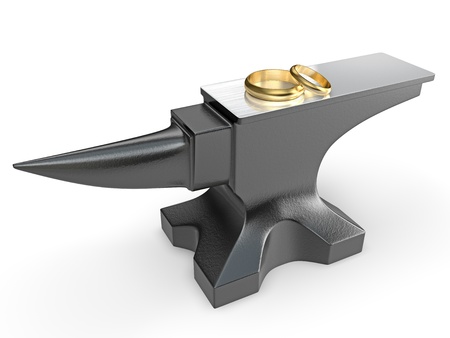 Two golden wedding rings on a metal anvil isolated on white backgroundの写真素材