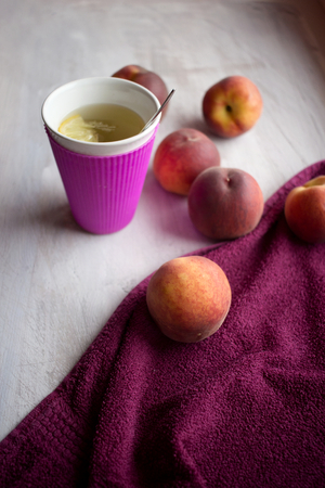 sweet fresh peaches on white wooden background with lemon teaの写真素材