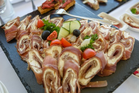 Meat rolls stuffed with cheese displayed on black plateの写真素材