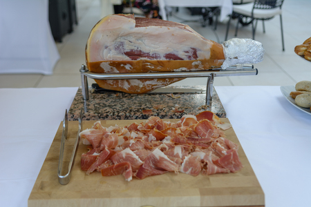 Dried ham also known as prosciutto sliced and displayed on wooden boardの写真素材