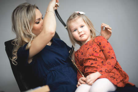 Friendly doctor female examining a little girl by stethoscopeの写真素材