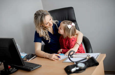 Friendly doctor female examining a little girl by stethoscopeの写真素材