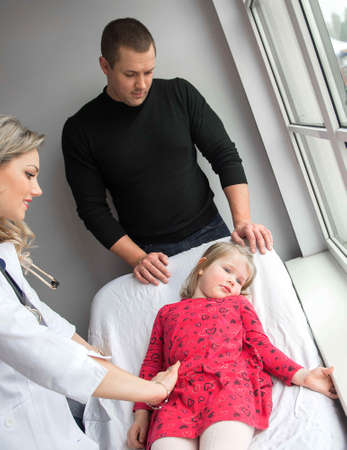 Father with girl being examined by friendly female pediatrician in clinicの写真素材