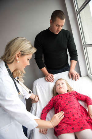 Father with girl being examined by friendly female pediatrician in clinicの写真素材
