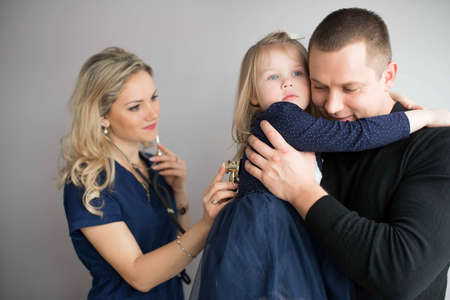 Father with girl being examined by friendly female pediatrician in clinicの写真素材