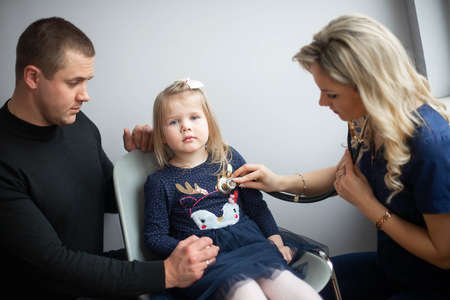 Father with girl being examined by friendly female pediatrician in clinicの写真素材