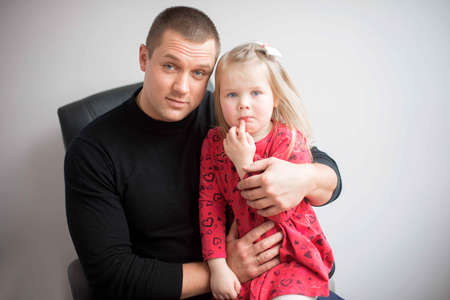 Emotional portrait of father and little  daughter on a gray studio backgroundの写真素材
