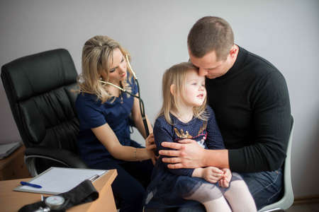 Father with girl being examined by friendly female pediatrician in clinicの写真素材