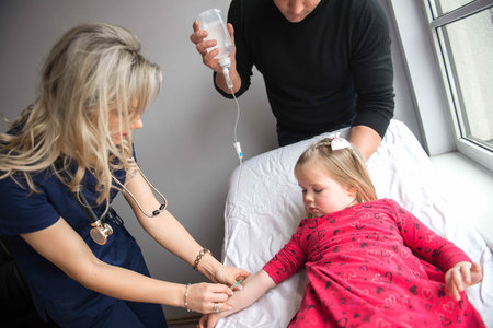 Father with girl being examined by friendly female pediatrician in clinicの写真素材