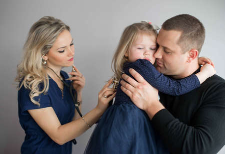 Father with girl being examined by friendly female pediatrician in clinicの写真素材