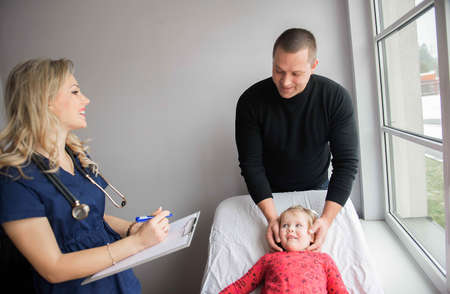 Father with girl being examined by friendly female pediatrician in clinicの写真素材
