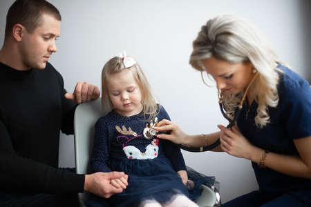 Father with girl being examined by friendly female pediatrician in clinicの写真素材