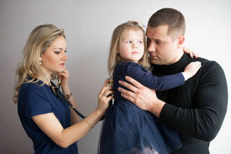 Father with girl being examined by friendly female pediatrician in clinicの写真素材