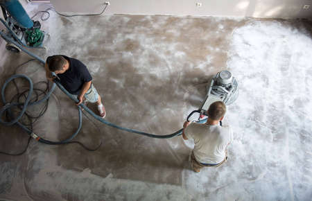 Construction worker in a family home living room that grind the concrete surface before applying epoxy flooring.Polyurethane and epoxy flooring.Concrete grinding.の写真素材