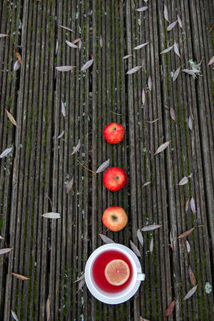 Hot fruit tea with lemon slice in white mug on woodenbackground, cozy hot winter drink conceptの写真素材